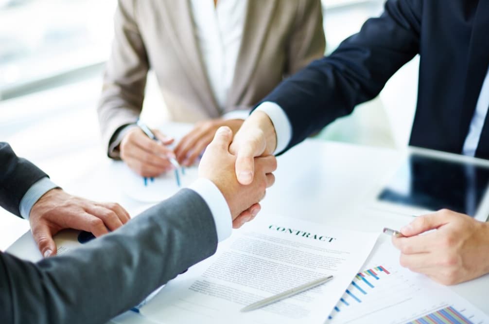 Close-up of a handshake over a business contract