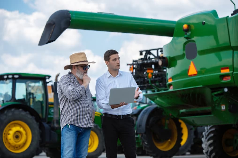 A farmer and businessman discuss machinery, symbolizing agricultural planning